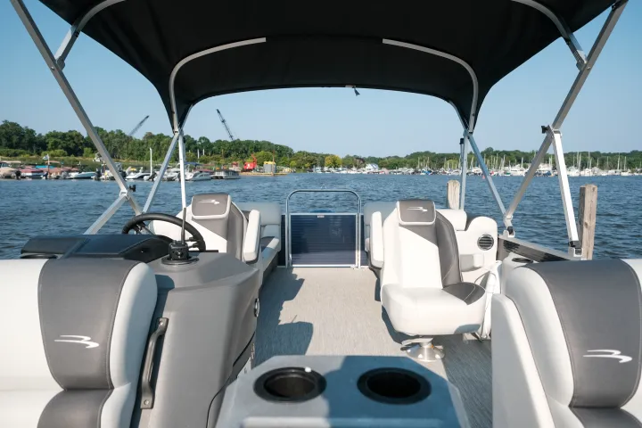 Interior of a pontoon boat with shaded seating, overlooking a marina.