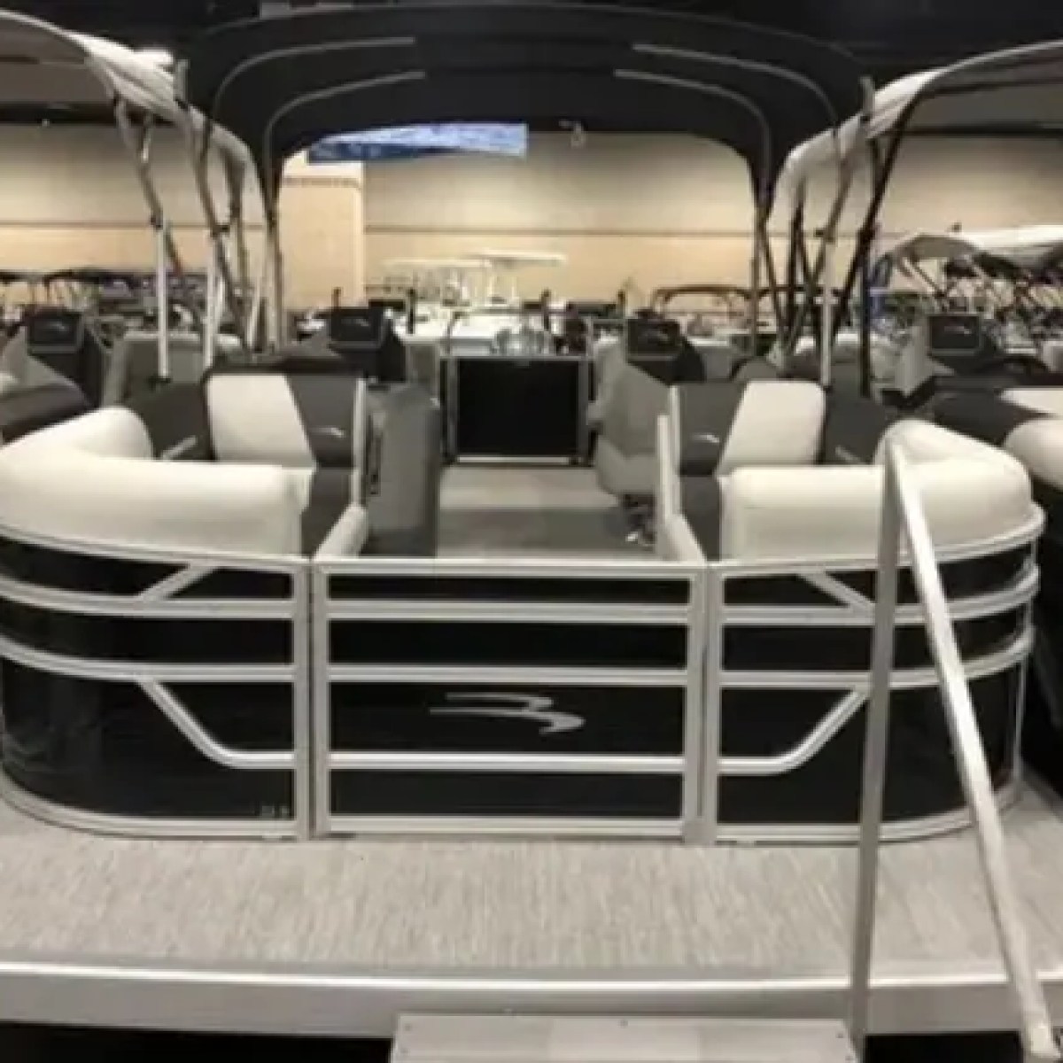 Pontoon boats with gray seating arranged at a boat show display.