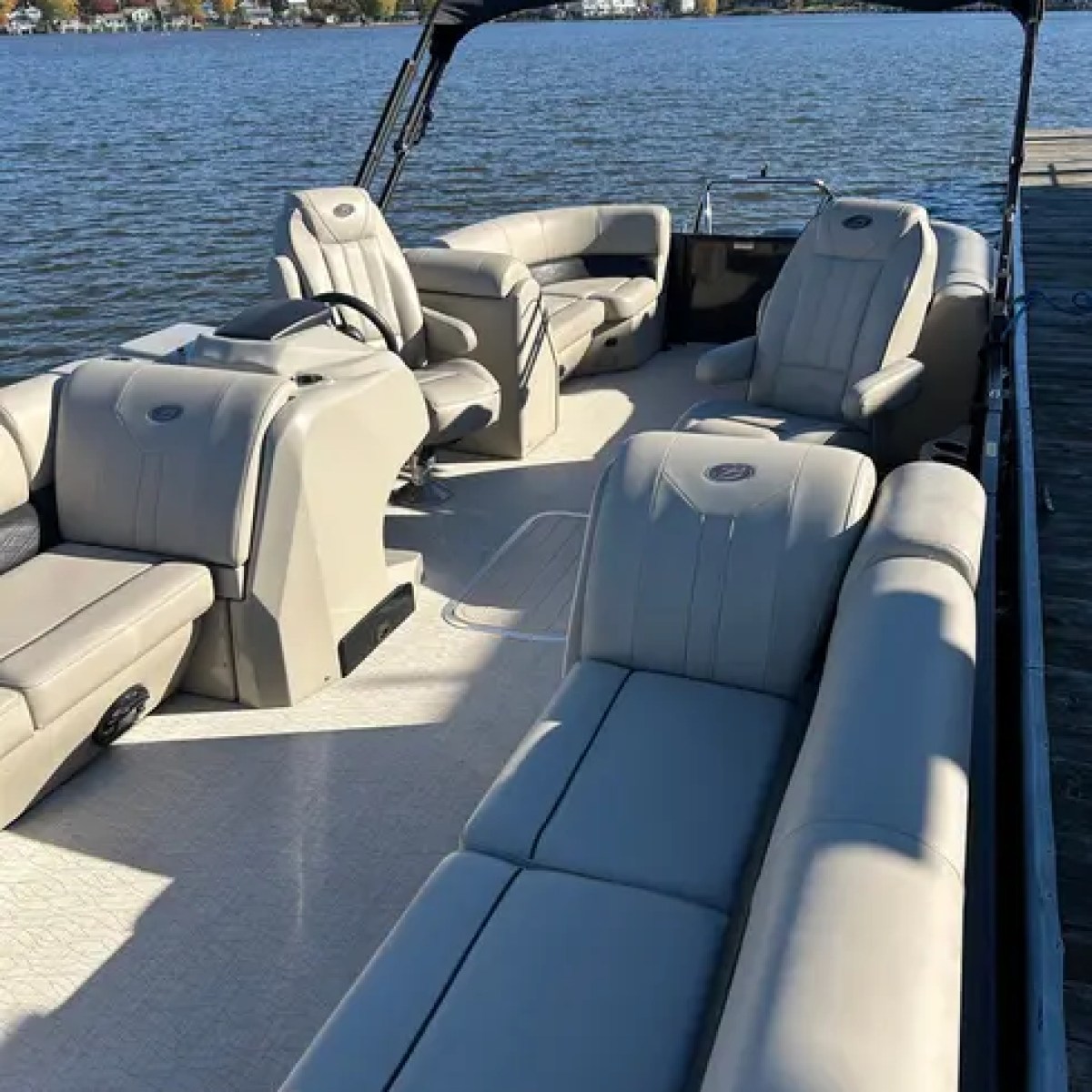 Interior of a pontoon boat with beige seating on a calm lake.