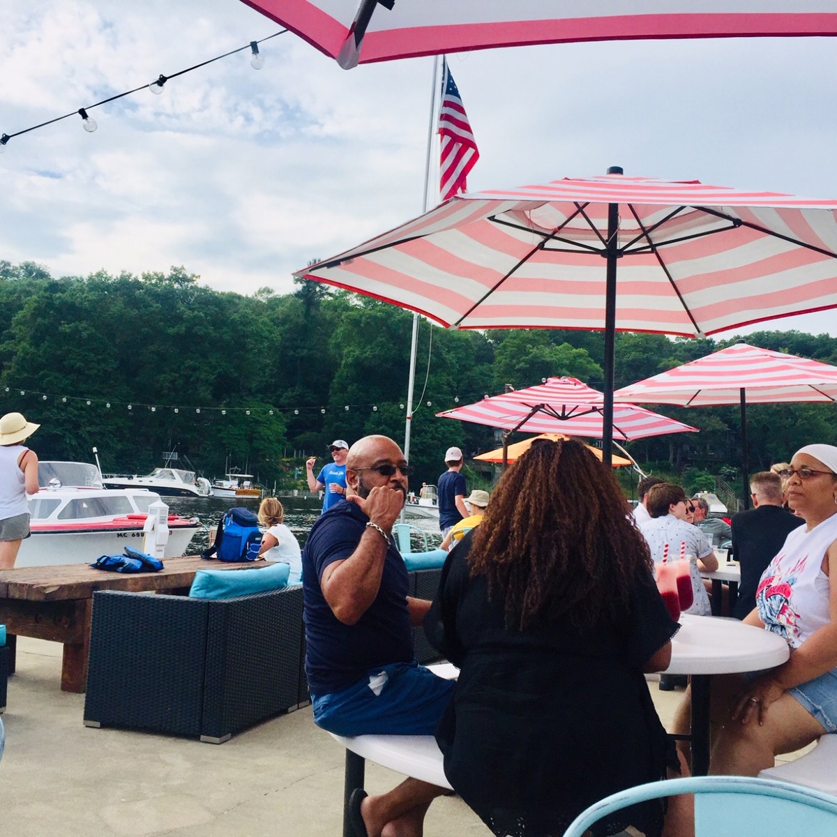 a group of people sitting at a table with a blue umbrella