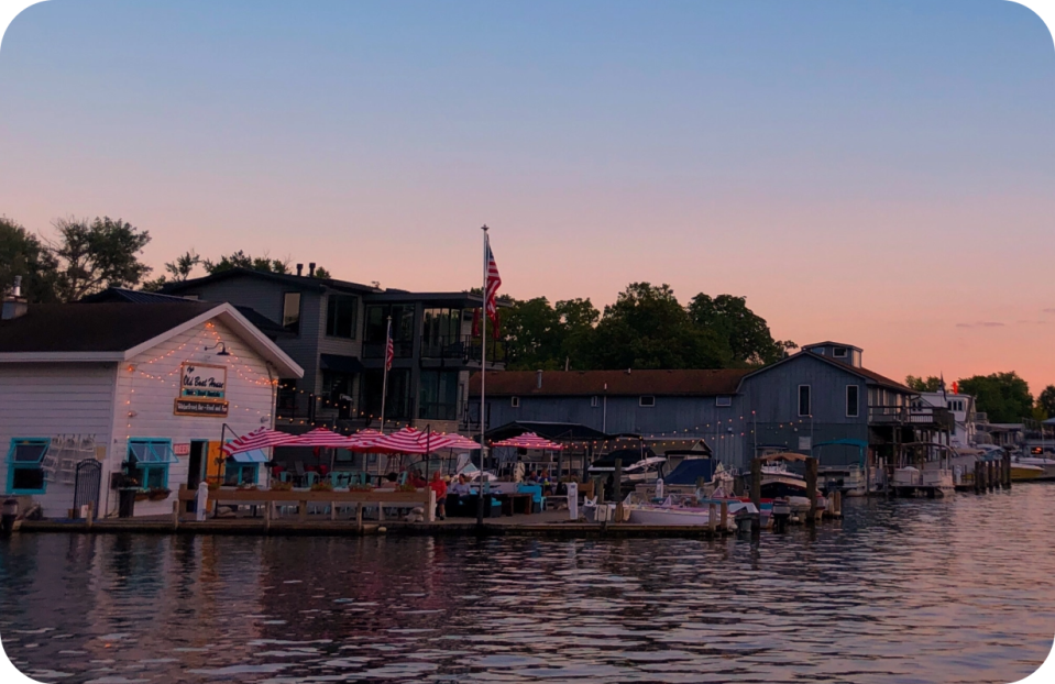 Waterfront buildings and boats at sunset with pink umbrellas.